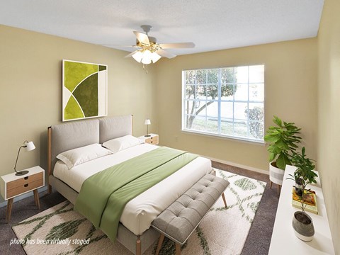 A bedroom with a bed, a ceiling fan, and a window.