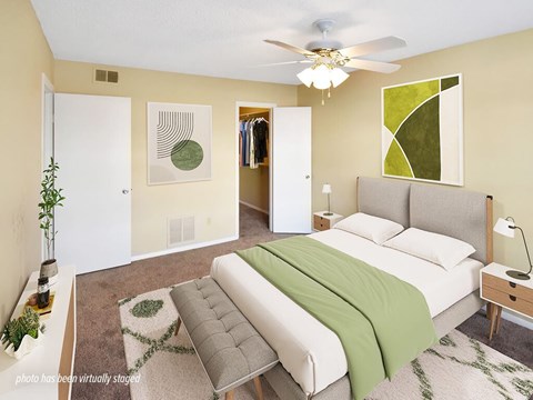 A bedroom with a bed, a couch, and a ceiling fan.