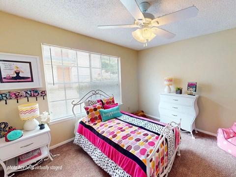 A bedroom with a bed, dresser, and window.