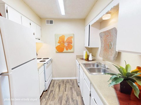A kitchen with a white fridge, a sink, and a painting on the wall.