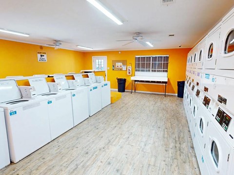 A laundromat with rows of washing machines and a fan on the ceiling.