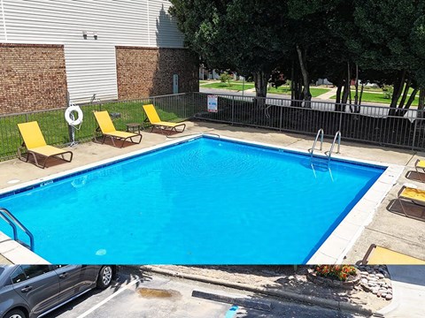 A small pool with a fence around it and a car parked in front.