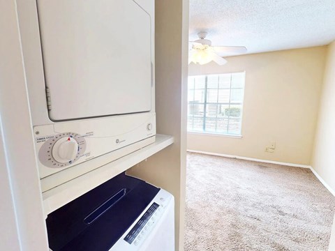 A white dishwasher is in a kitchen next to a window.