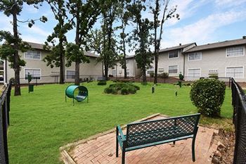 a park bench overlooking a green yard with houses in the background