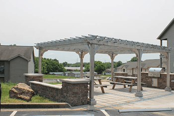 a patio with a picnic table and a grill