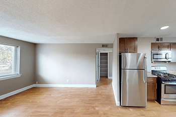 A kitchen with a stainless steel refrigerator and wooden floors.