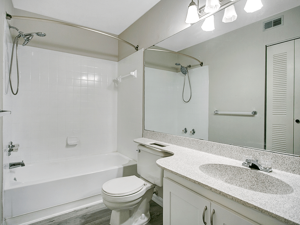 Full bathroom at the Earl Apartments with shower, tub, and large mirror