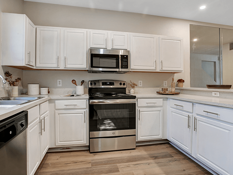 a white kitchen with stainless steel appliances and white cabinets