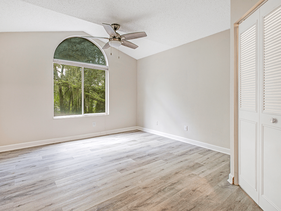 Large bedroom with window and hard wood flooring