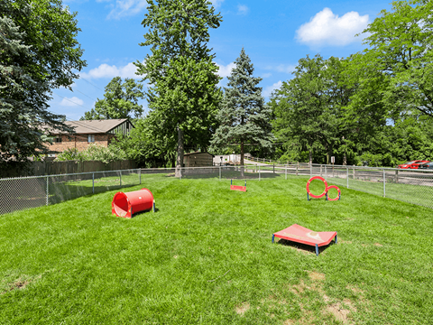 fenced in dog park with agility equipment at Whispering Timbers Apartments