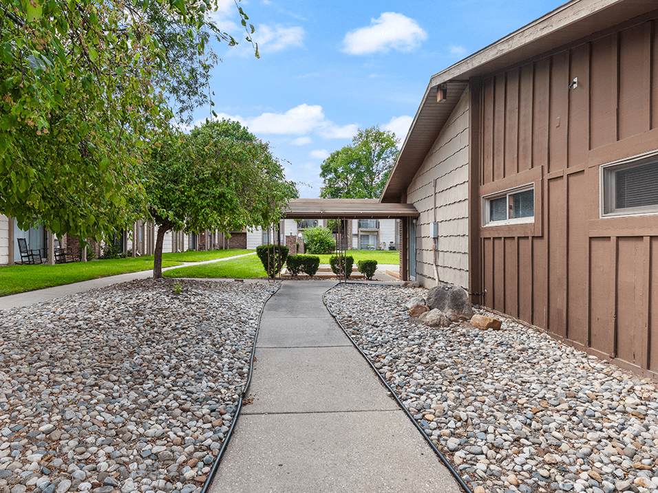 a walkway leading to a house with gravel and trees
