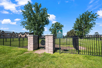 A sign in front of a fence with a tree behind it.