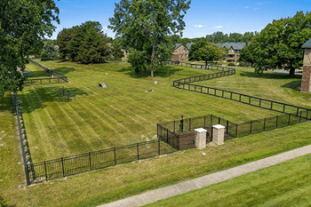 A black fence surrounds a grassy area with a small building in the background.