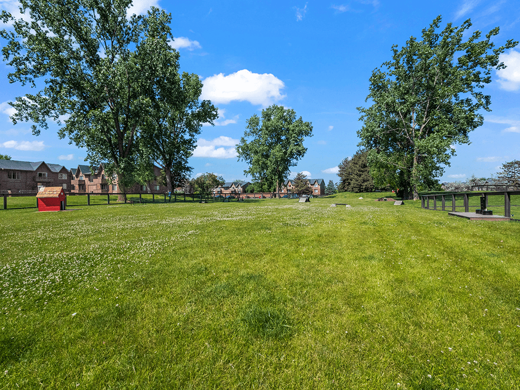 A grassy field with trees and a red object in the distance.