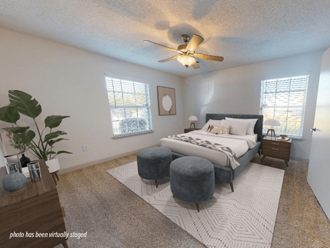 A bedroom with a bed, nightstand, and a plant.