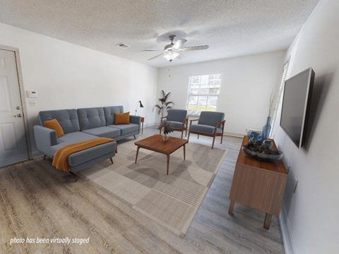 A living room with a grey couch, a wooden coffee table, and a television.