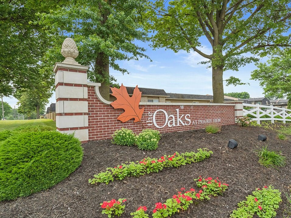 the sign at the entrance to the oaks community with flowers and trees