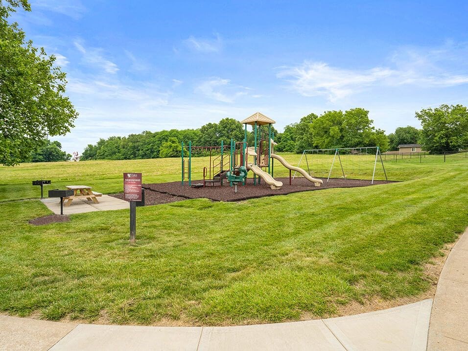 a large grassy field with trees and a clock tower
