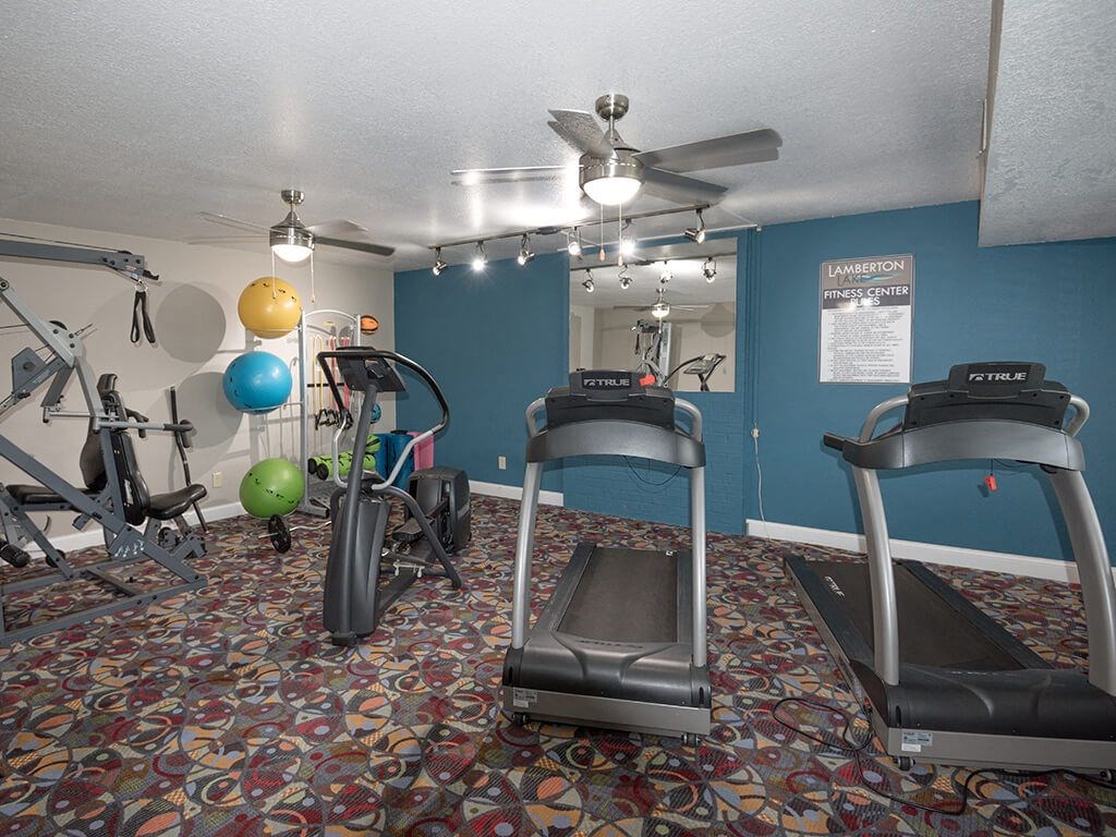 a gym with exercise equipment and a ceiling fan