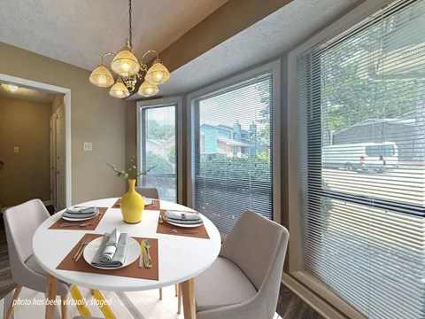 A dining room with a table set for two and a view of the street outside.