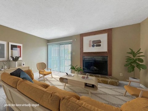 A living room with a yellow couch and a fireplace.