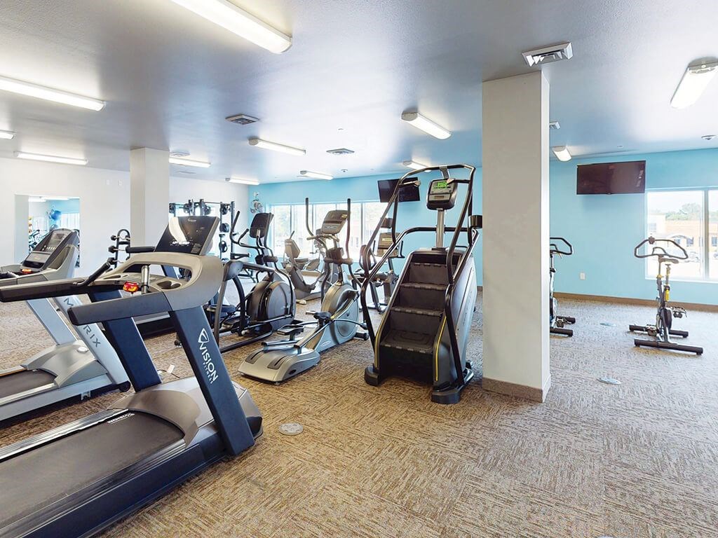An exercise room with weights and machines at The Plaza Apartments.