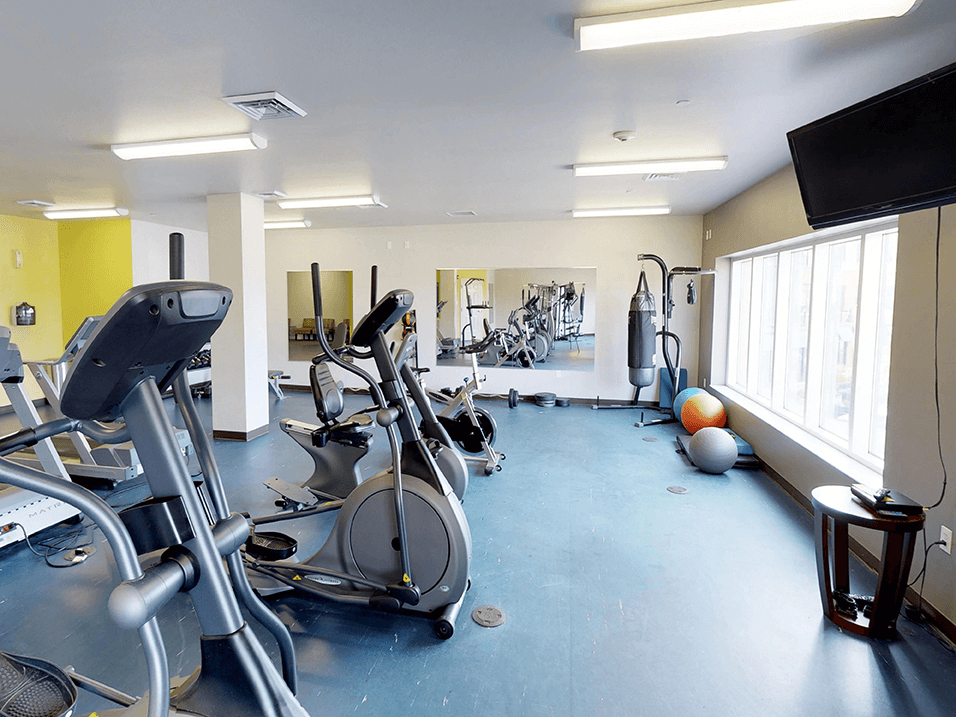 a gym with cardio equipment and a flat screen tv