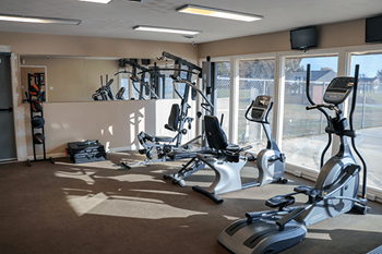 A gym with a variety of exercise equipment including treadmills, stationary bikes, and weight machines.