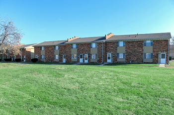 A large grassy field in front of a brick building.