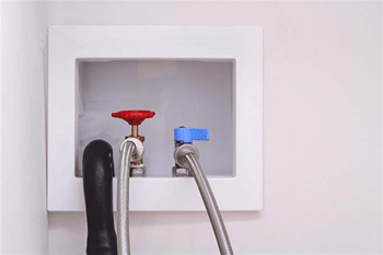 A red object is connected to a blue object with a grey hose.