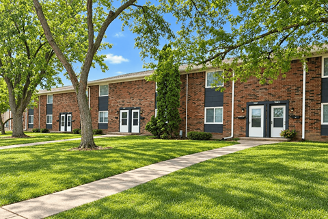 A tree in front of a brick building with a walkway in between.