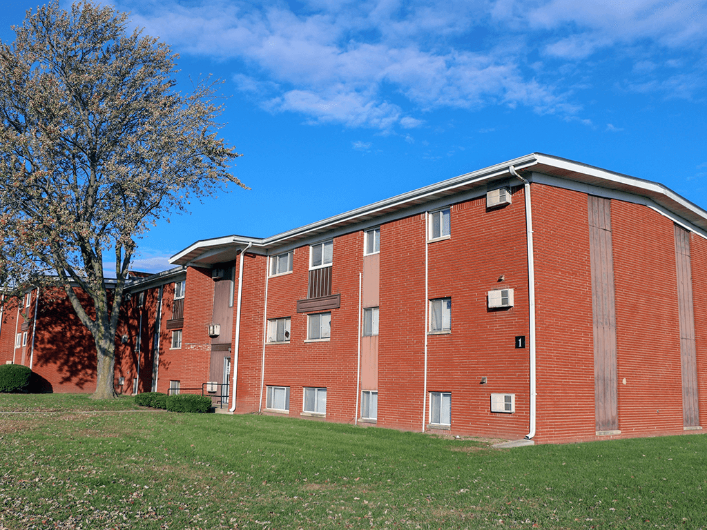 A red brick building with a tree in front of it.