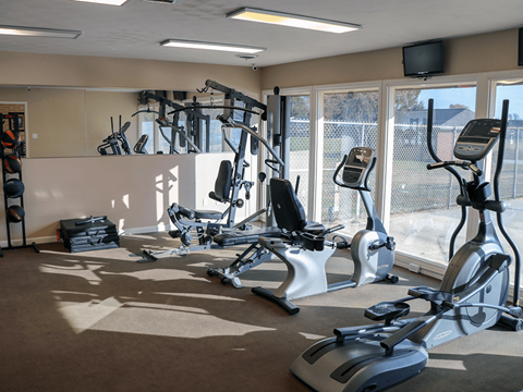 A gym with a row of exercise bikes and a television on the wall.