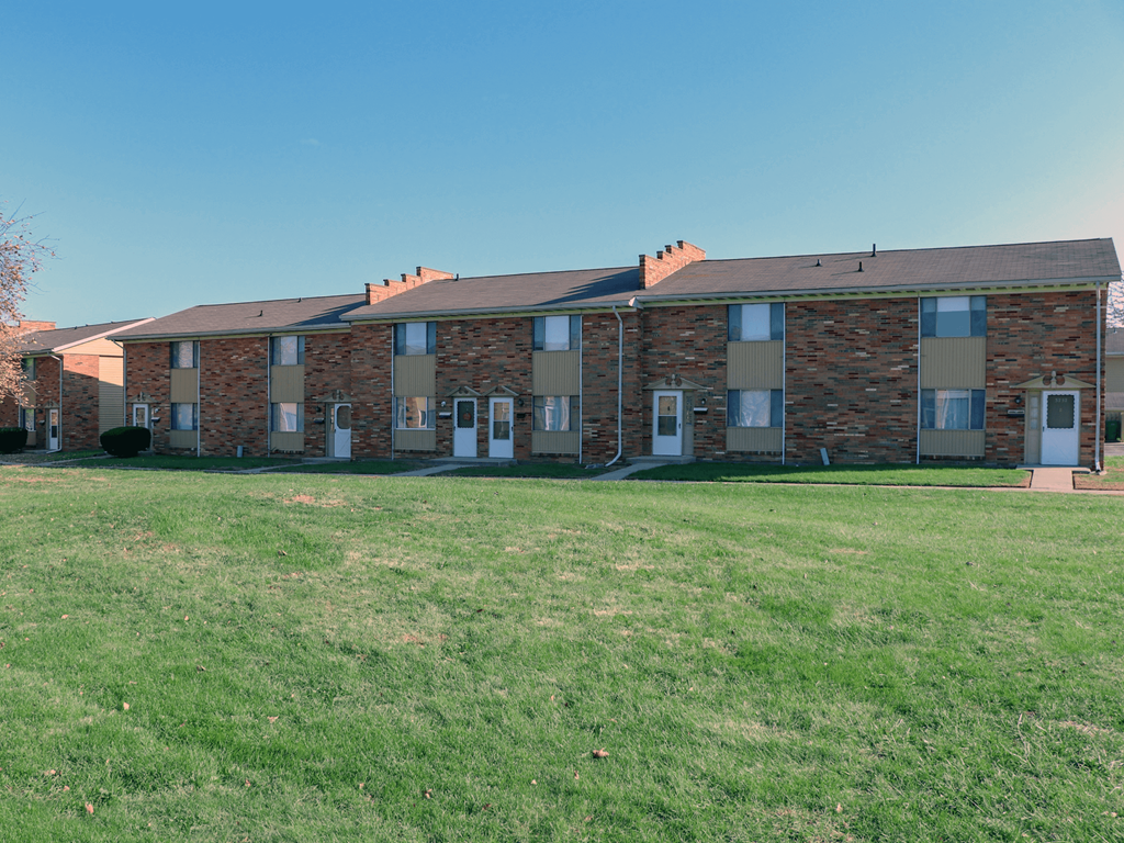 A row of houses with a green lawn in front.