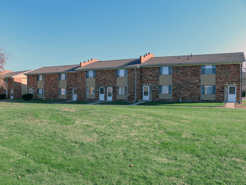 A row of houses with a green lawn in front.