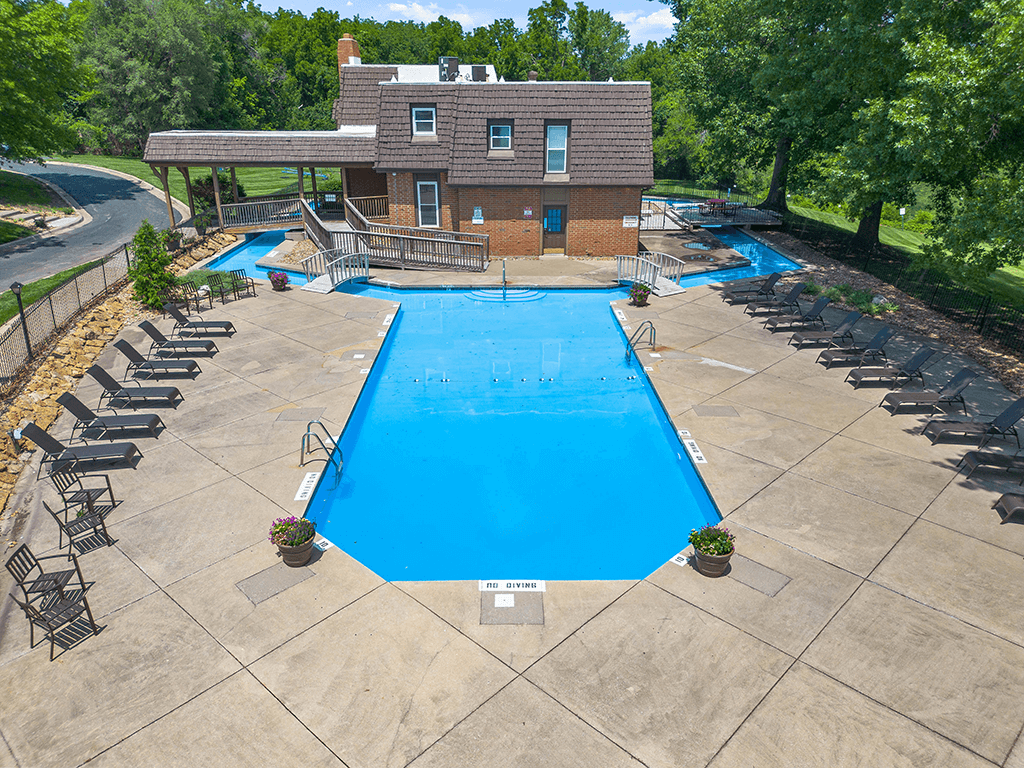an aerial view of a swimming pool with a house in the background