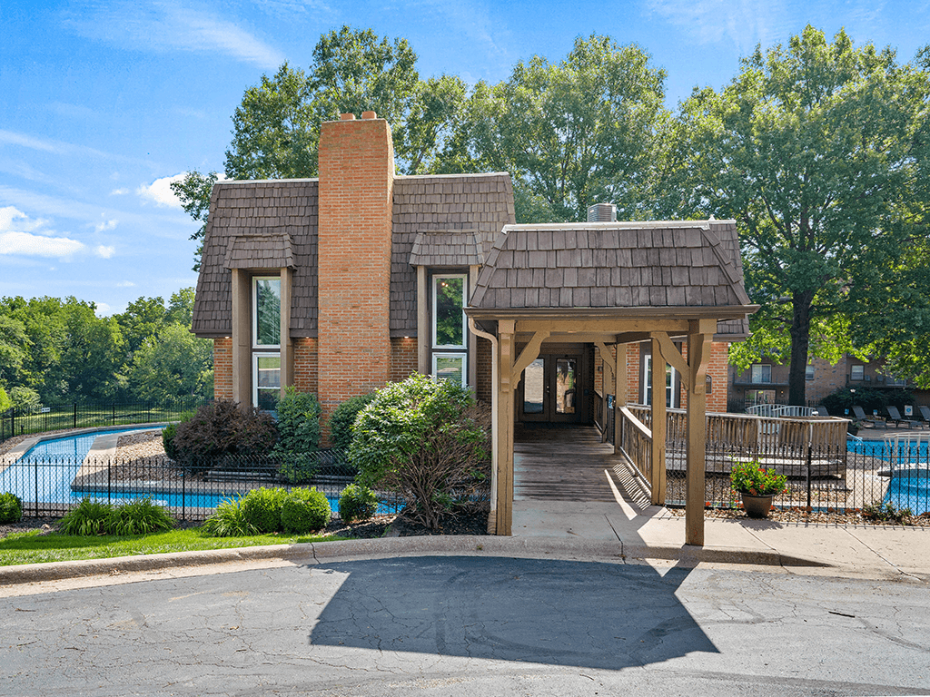 a building with a covered porch next to a swimming pool