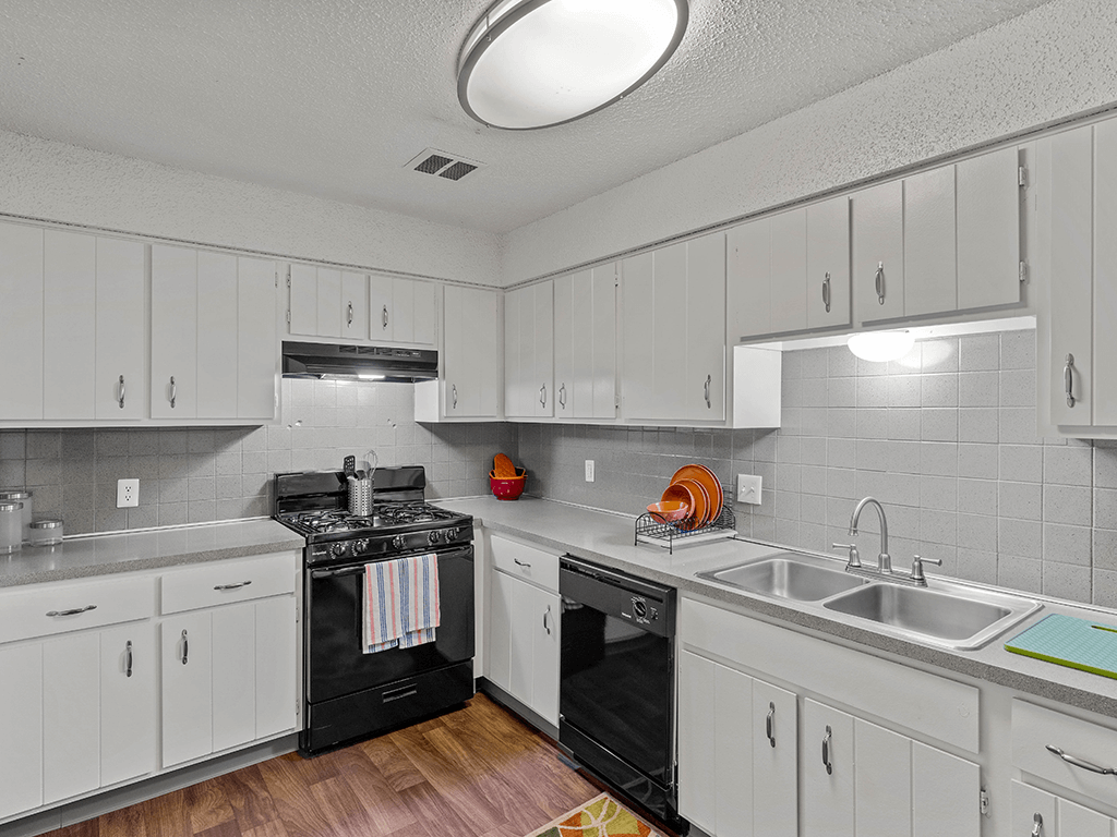 a kitchen with white cabinets and black appliances and a sink
