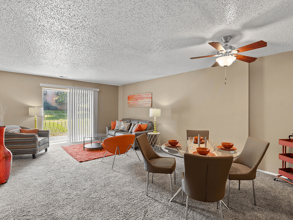 a living room with a table and chairs and a ceiling fan