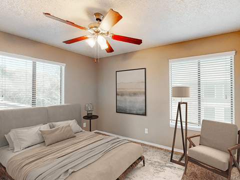 a bedroom with a ceiling fan and two windows