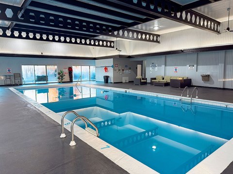 A large indoor swimming pool with a diving board.