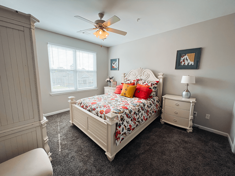 A bedroom with a large bed and a ceiling fan.