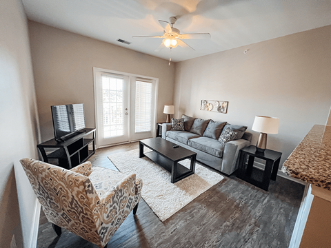 A living room with a leopard print chair and a grey couch.