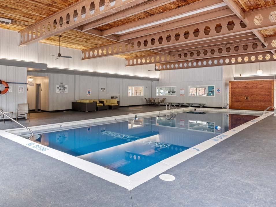 a large indoor swimming pool with a wooden ceiling