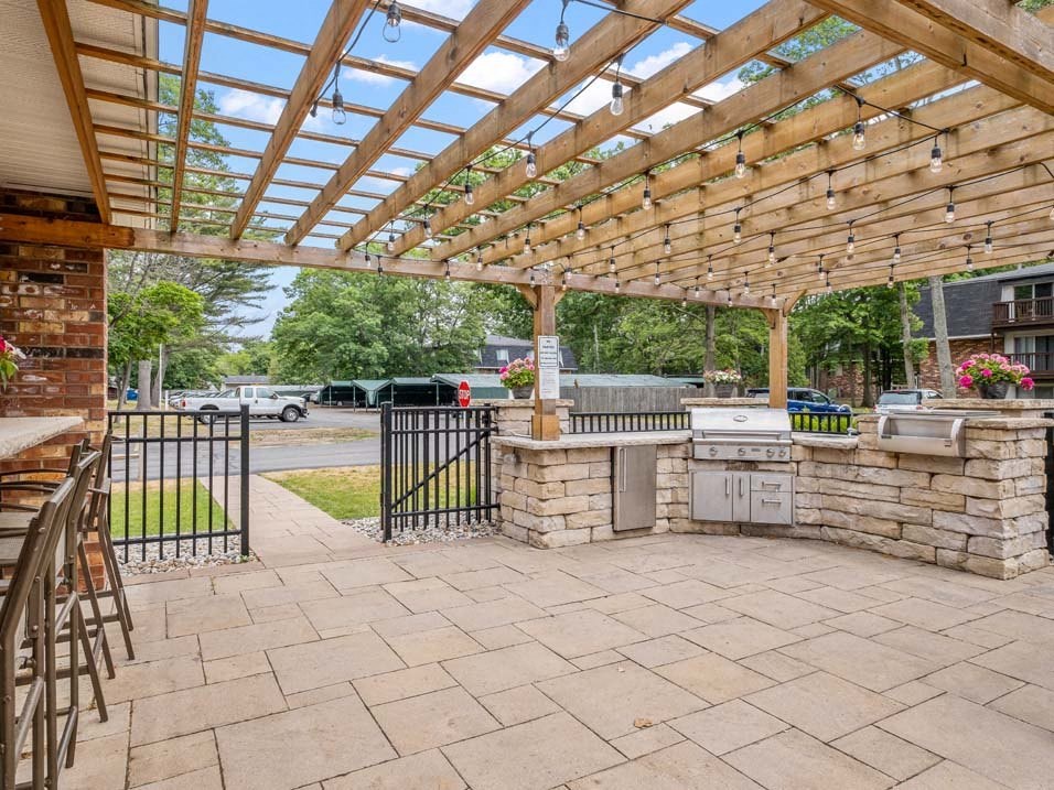 a patio with a pergola and an outdoor kitchen
