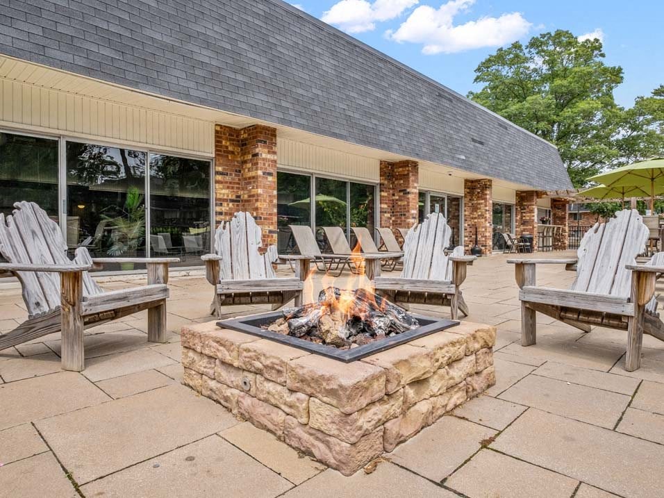 a patio with a firepit and chairs outside of a building