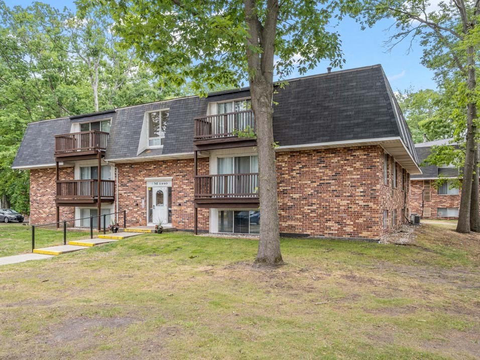 a brick building with a white door and a large tree in front of it