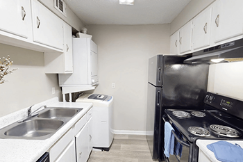 A kitchen with a black refrigerator, white cabinets, and a black stove.