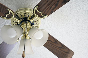 A ceiling fan with a light fixture and wooden blades.