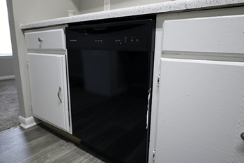 A black oven is built into a white cabinet.